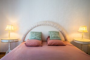 Una cama con dos almohadas, dos mesitas de noche y lámparas.