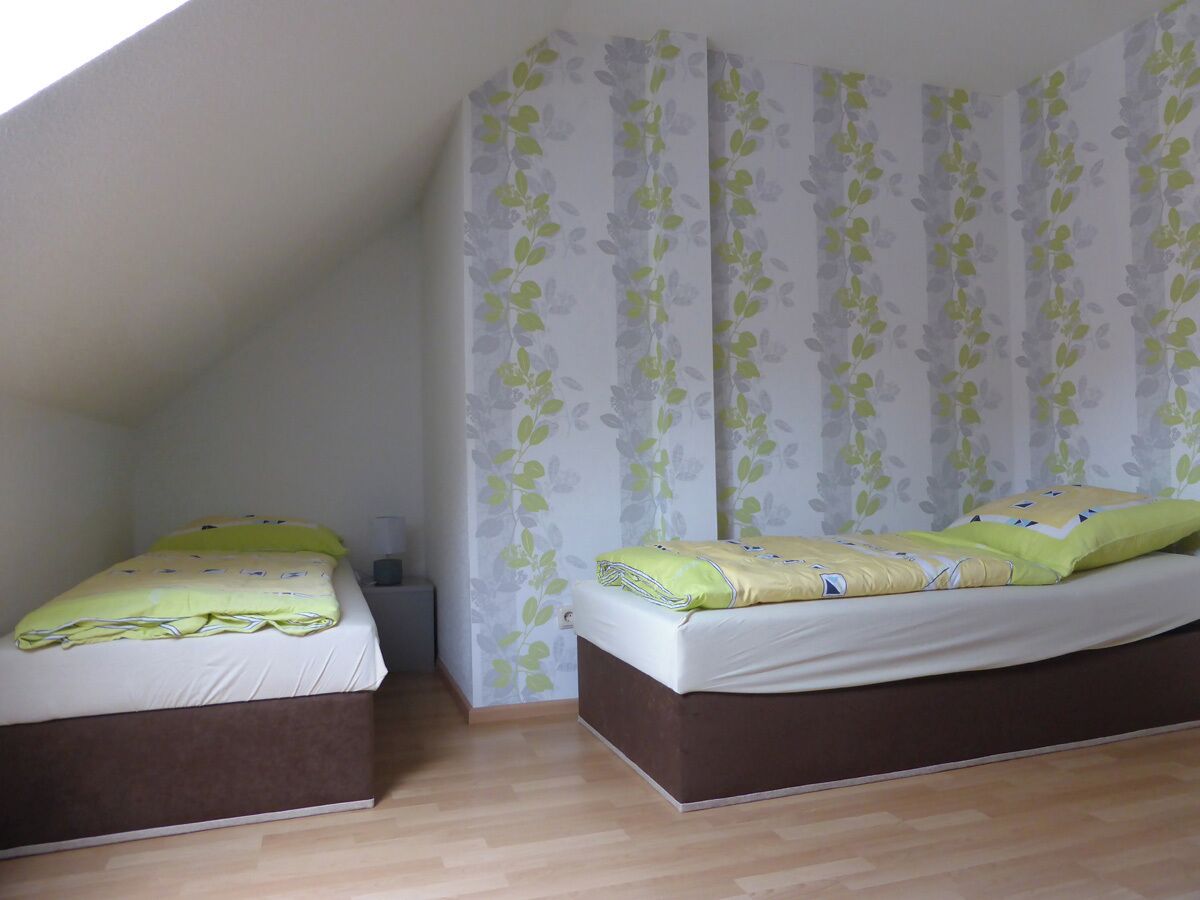 A room with two beds, a wooden floor, and a window.