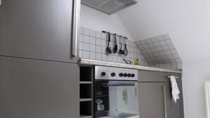 Une cuisine équipée d’un four encastré, d’une hotte en acier inoxydable et d’un pare-feu en carreaux.