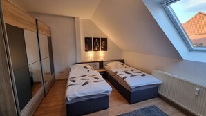 Une chambre avec deux lits, un puits de lumière et un radiateur.