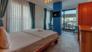 Hotellihuone, jossa on sänky, televisio, puinen pöytä ja näkymä ulos.