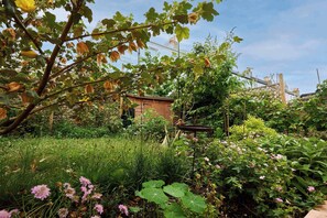 A garden with various plants and a small brick building.