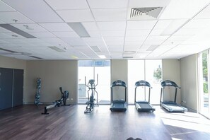Ein Fitnessstudio mit Laufbändern, Crosstrainern und Rudergeräten.