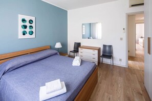 Ein Schlafzimmer mit Bett, Schreibtisch, Stuhl, Lampe und Spiegel.