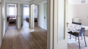 Ein Hotelzimmer mit Holzboden, einem Essbereich mit Tisch und Stühlen sowie einem Bett mit gestreifter Bettwäsche.
