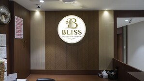Balcão de recepção de hotel com uma grande placa indicando 'BLISS Boutique Hotel' e um mural de avisos.
