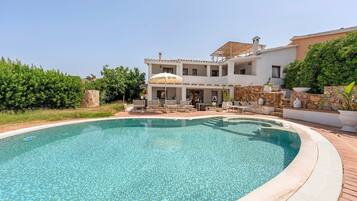Una casa de dos pisos con una piscina al frente.