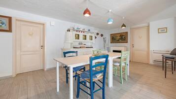 A dining area with a wooden table and chairs, a white cabinet with glass doors, and a painting on the wall.
