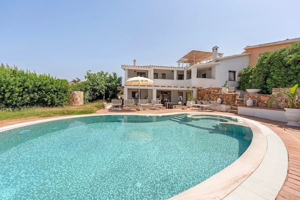 A two-story house with a swimming pool in the foreground.