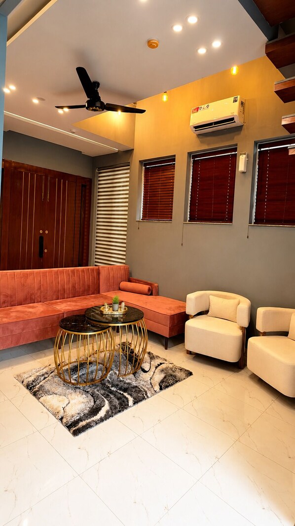 A modern living room with a sofa, armchairs, a coffee table, and a ceiling fan. - Spacious 3BR Home in DHA Rahbar - WiFi, Parking & 24/7 Support (Lahore)