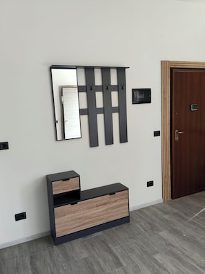 A room with a wooden door, a wall-mounted mirror, and a black console with drawers. - Spacious Apartment in a Convenient Location (Bergamo)