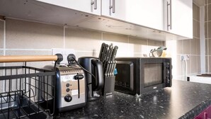 Una cocina con tostadora, microondas y un juego de cuchillos sobre la encimera.