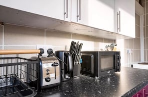 A kitchen with a toaster, microwave, and knife block on the counter.