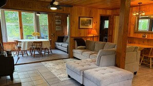 Um interior de madeira com um sofá, uma mesa de jantar e um ventilador de teto.