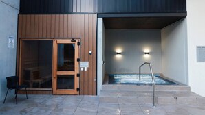 Entrada de um spa, com porta de madeira, banheira de hidromassagem e uma cadeira do lado de fora.