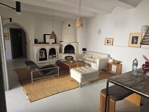 Un salon comprenant un canapé, un pouf, une table basse et une cheminée.