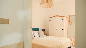 A bedroom with a bed, a bedside table, a lamp, a wardrobe, and a hanging light fixture. - Casa Totò - Ocean View in the Center of Otranto Terrarossa Luxury Home (Otranto)