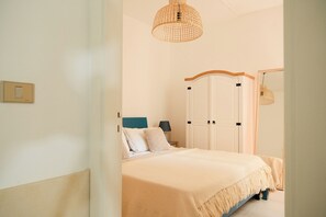 Ein Schlafzimmer mit einem Bett, einem Nachttisch, einer Lampe, einem Kleiderschrank und einer Deckenleuchte.