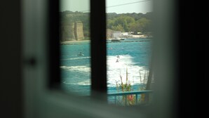 A view through a window of a coastal scene with cliffs, a body of water, and a distant shoreline. - Casa Totò - Ocean View in the Center of Otranto Terrarossa Luxury Home (Otranto)