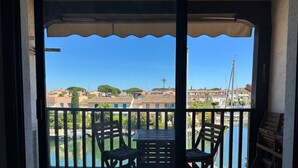 Un balcón con mesa y sillas, con vista a un cuerpo de agua y edificios.