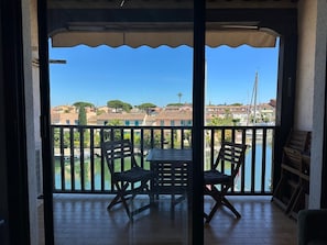 Ein Balkon mit Tisch und Stühlen mit Blick auf ein Gewässer und Gebäude.