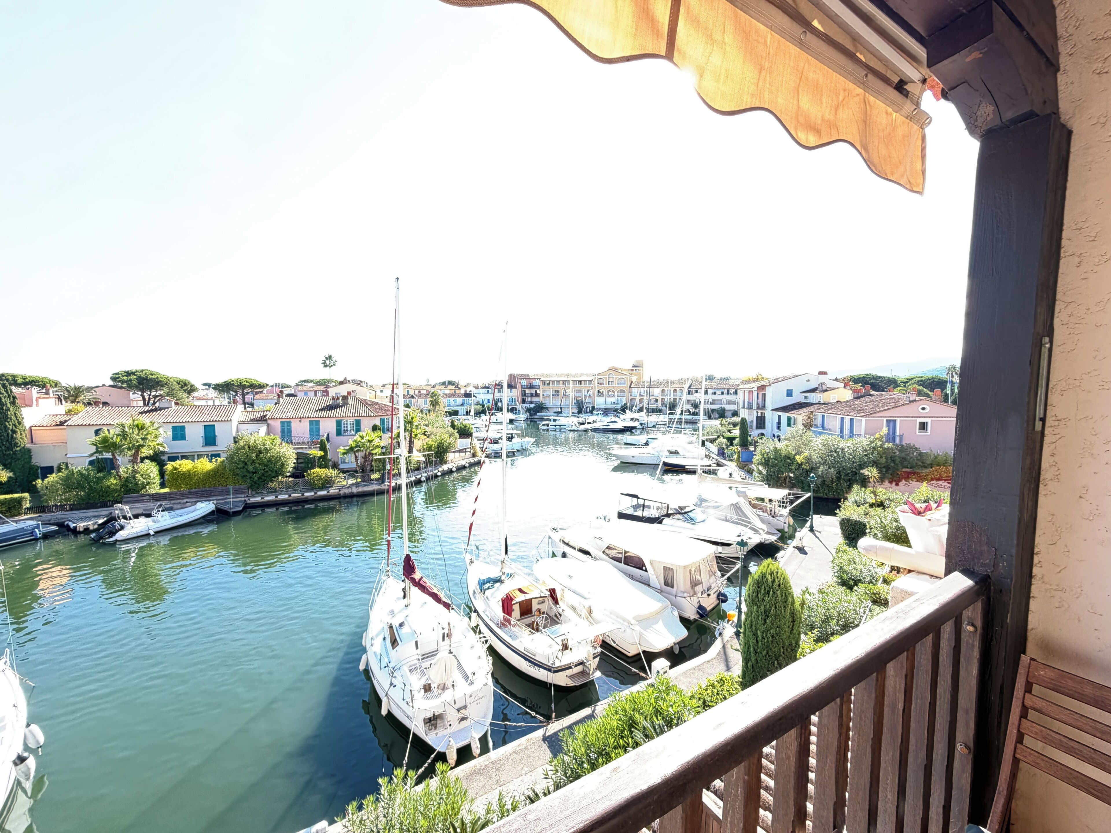 A marina with boats docked, a balcony overlooking the water, and buildings in the background.