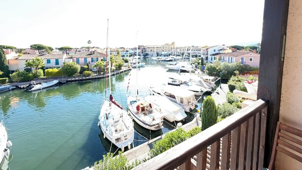 Un puerto deportivo con barcos amarrados, un balcón con vistas al agua y edificios al fondo.