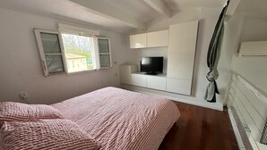 Un dormitorio con una cama, un televisor y una ventana.