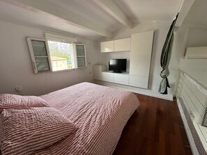 Ein Schlafzimmer mit einem Bett, einem Fernseher und einem Fenster.