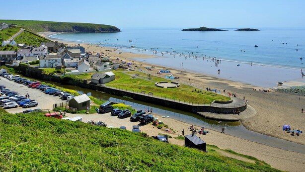 A coastal town with a beach, a canal, and parked cars.