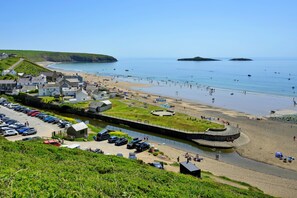 A coastal town with a beach, a canal, and parked cars. - Gladstone (Aberdaron)