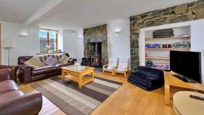 A living room with a stone wall, a fireplace, a sofa, a coffee table, and a television.