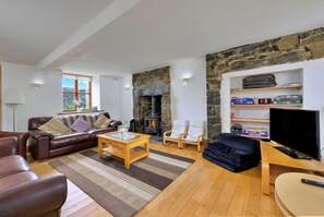 Ein Wohnzimmer mit Steinwand, Kamin, einer Couch, einem Couchtisch und einem Fernseher.