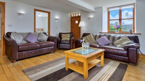 A living room with two leather sofas, a wooden coffee table, and a large window with a view.