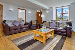 Ein Wohnzimmer mit zwei Ledersofas, einem Holztisch und einem großen Fenster mit Blick.