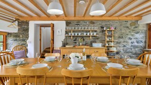 A wooden dining table set with plates, glasses, and a vase of flowers.