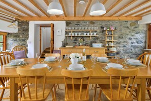 Ein Holztisch ist gedeckt mit Tellern, Gläsern und einer Blumenvase.
