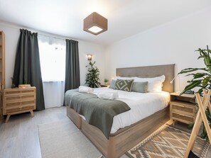 Ein Schlafzimmer mit Bett, Nachttischen, einem Topf mit Pflanze und einem Fenster mit Vorhängen.