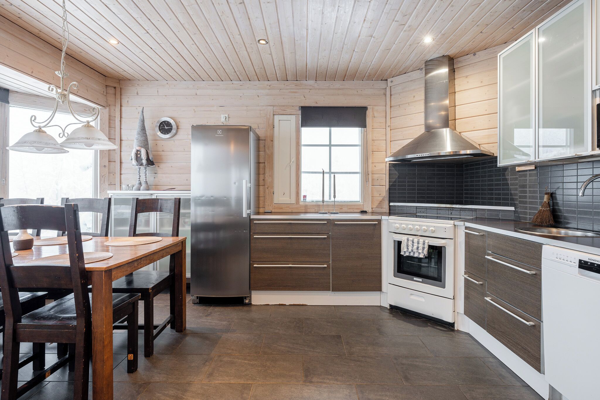 Una cocina moderna con armarios de madera, electrodomésticos de acero inoxidable y un comedor con mesa y sillas de madera.