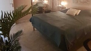 Un dormitorio con una cama, un espejo grande, una estatua de Buda y una planta en maceta.
