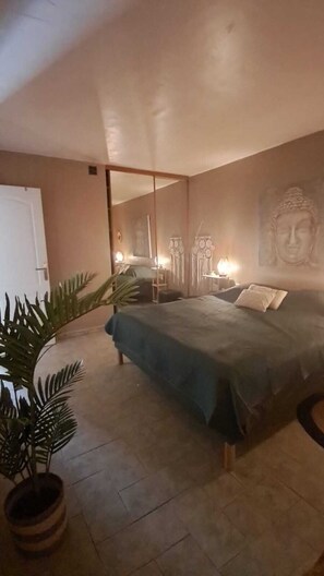 A bedroom with a bed, a large mirror, a Buddha statue, and a potted plant. - Quiet house with an outdoor spa (Roquebrune-sur-Argens)