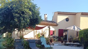 Una casa con patio, mobiliario exterior y jardín.