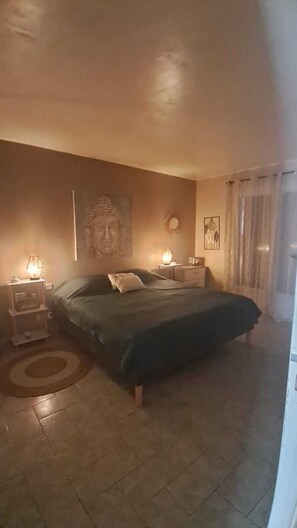 A bedroom with a bed, nightstands, a Buddha statue, a wall clock, and a painting. - Quiet house with an outdoor spa (Roquebrune-sur-Argens)