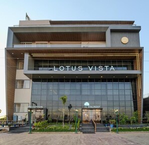 Un bâtiment moderne avec une enseigne indiquant « LOTUS VISTA », un espace d’accueil et l’entrée d’un restaurant.