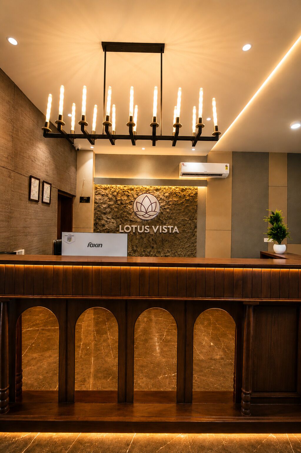 A reception desk with a logo, a nameplate, and a wall-mounted air conditioning unit.