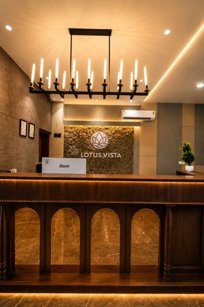 A reception desk with a logo, a nameplate, and a wall-mounted air conditioning unit. - Lotus Vista Hotel (Ramgarh)
