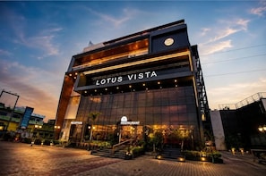 Un bâtiment moderne avec une enseigne indiquant « LOTUS VISTA », un espace d’accueil et l’entrée d’un restaurant.
