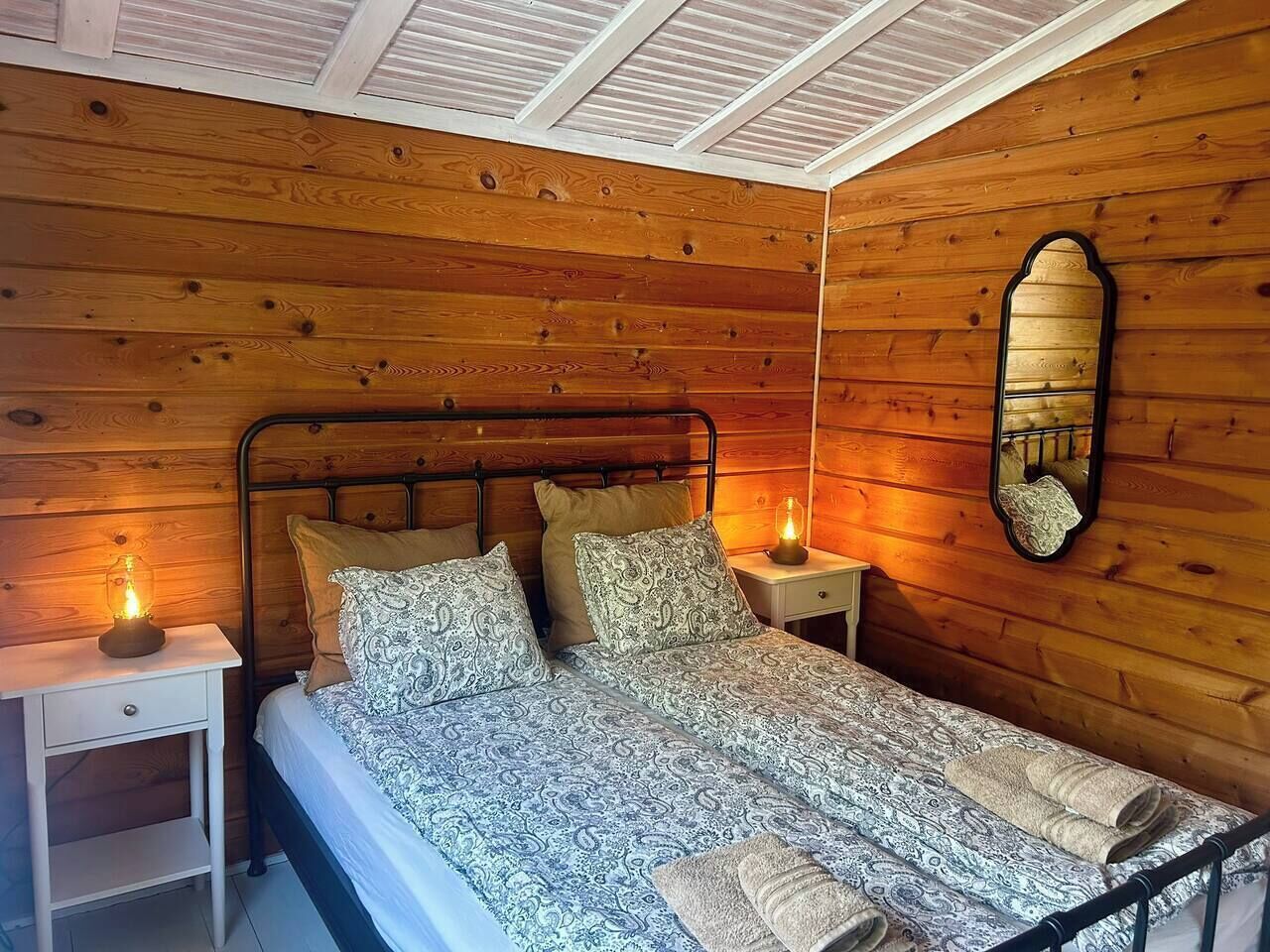 Une chambre à coucher aux murs lambrissés, avec un lit, deux tables de chevet et un miroir.