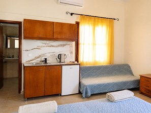 Una habitación compacta con kitchenette, cama y baño.