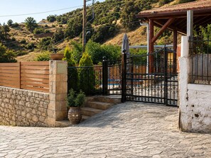 A stone wall, a metal gate, and a paved entrance to a property. - Villa Maria Christina With Private Pool in Crete (Faistos)